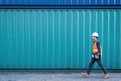 1087736054 engineer walking in shipping container yard and copy space